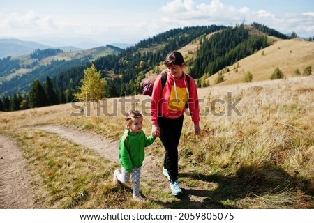 Mother and daughter hiking in the mountains.The concept of family travel, adventure, and tourism. Lifestyle autumn vacations outdoor.