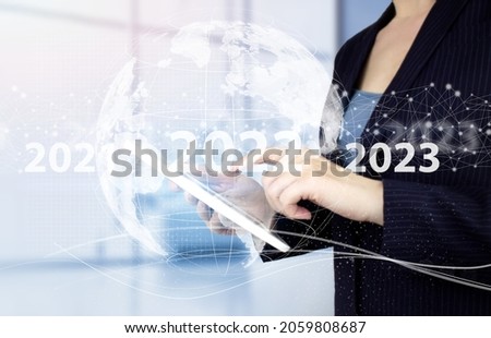 Happy New Year 2022 - Hand touch white tablet with digital hologram 2022 sign on light blurred background. Concept for vision 2021-2022. Businessman welcome year 2022