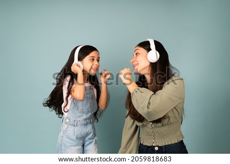 Sing with me. Hispanic young mom and little girl singing together while listening to music with headphones  Royalty-Free Stock Photo #2059818683