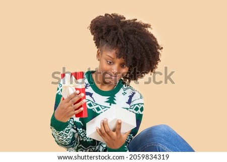 pretty afro american woman, at christmas with gift, beige background