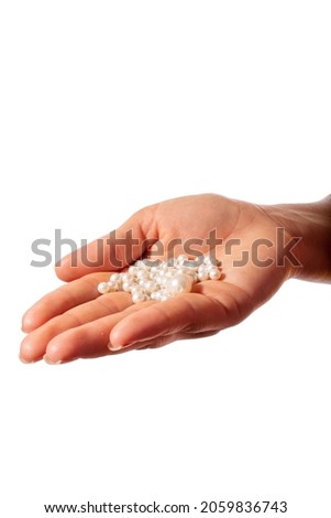 Woman's hand with a handful of white pearls for necklace. Isolated on white background.