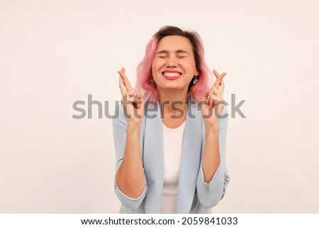 Portrait of hopeful woman waiting, making wish, cross fingers for good luck and smiling, anticipating good news results, standing over white background