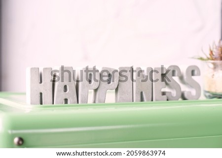 Gray letters means happiness placed on green plastic board. Horizontal studio shot.