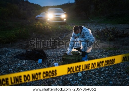 Forensic police investigator collecting evidence at the crime scene in nature at night Royalty-Free Stock Photo #2059864052
