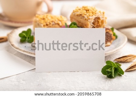 White paper business card and set of eclair on gray concrete background. side view, close up, selective focus, still life. Breakfast, morning, concept.