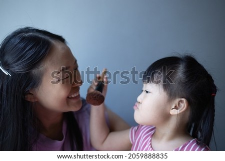 Asian little daughter doing make up her mom. Concept of love and connection of mother and kid.