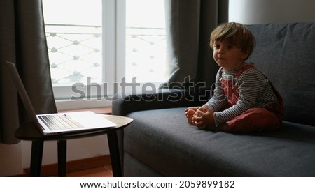 Child sitting on sofa watching cartoons on computer