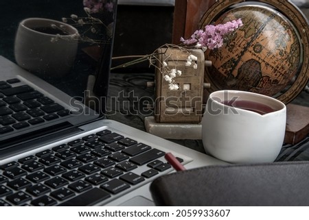 Workplace side view with laptop screen, keyboard, globe, desktop calendar, flower, fruit juice mug and notebook with pencil at office workplace. Creative concept. No focus, specifically.