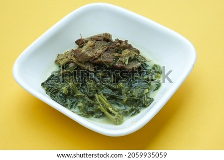 Close up picture Malay dish called "masak lemak pucuk ubi daging salai daging salai". It is made of cassava leaves, lemongrass, coconut milk and curry spice together with smoke beef.