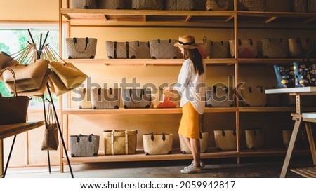 Traveler or business owner woman in souvenir shop, Tourist girl looking Krajood hand bags display on shelf in local handmade store, female travel Phatthalung Thailand, Tourism beautiful place Asia Royalty-Free Stock Photo #2059942817