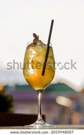Glass of cold water with ice cubes and apple syrup against the background of the city. Photo