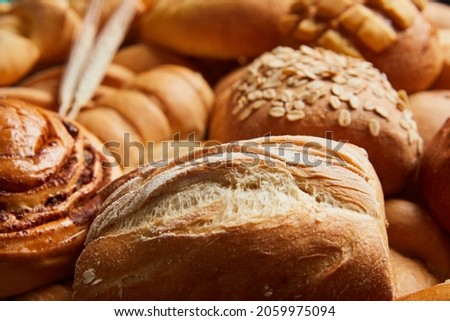 Close up of different types of breads and golden buns with ears of wheat. Food and bakery concept. Salty and sweet food. Bakery and carbohydrates. Horizontal photo. Royalty-Free Stock Photo #2059975094