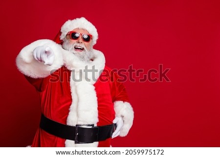 Portrait of attractive cheerful confident Santa pointing at you copy space select isolated over bright red color background