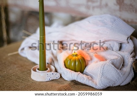 burning green candles for Halloween, evening atmosphere of a cozy house on memorial day, a pumpkin-shaped candle on a knitted fabric background