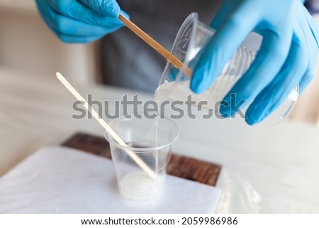 Mixing process of two resin components for creativity, gloved hands, resin art master class Royalty-Free Stock Photo #2059986986