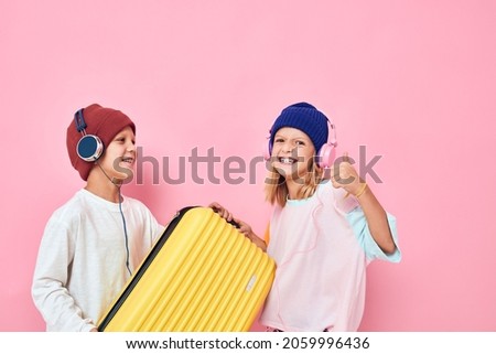 joyful boy and girl with a yellow suitcase in his hands Childhood lifestyle concept