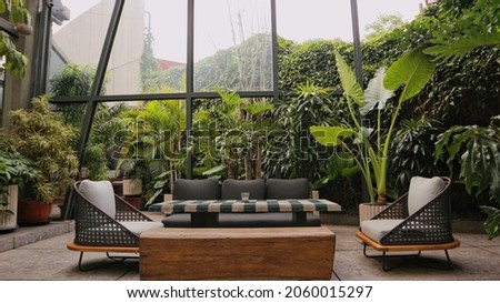 Modern living room with gray sofa and green tropical ferns outdoors Royalty-Free Stock Photo #2060015297