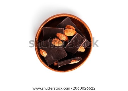 Dark chocolate with cocoa and whole almond isolated on a white background. Chocolate pieces in wooden bowl. High quality photo