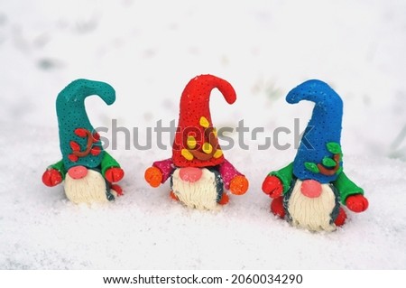 Figures of multi-colored gnomes in a snowy forest. Fairy tale characters.