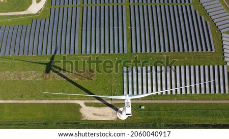 Aerial top down view of  solar park and a wind turbine both technologies convert nature's kinetic energy into electrical power providing renewable sustainable and ecological electricity Royalty-Free Stock Photo #2060040917