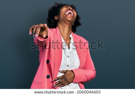 African american woman with afro hair wearing business jacket laughing at you, pointing finger to the camera with hand over body, shame expression  Royalty-Free Stock Photo #2060046605