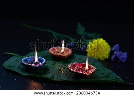 Eco Friendly Handcrafted Colorful Clay Diya Deep Or Dia Illuminated On Green Leaf With Flowers. Indian Festival Theme For Diwali Pooja, Navratri, Dussehra Puja, Deepawali Or Shubh Deepavali