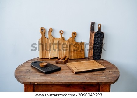 Kitchen utensils made of wood. On the table there are several different wooden boards, a set of light boards and two long textured boards, as well as a bowl for spices