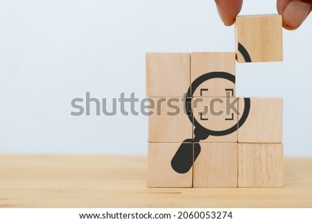 Identify and clarify concept. Market and customer target and focusing. Hand hold the wooden cubes with magnifying glass and cropped object symbols on white background with copy space. SEO concept. Royalty-Free Stock Photo #2060053274