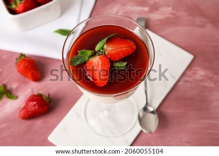 Tasty strawberry panna cotta in glass on color background, closeup