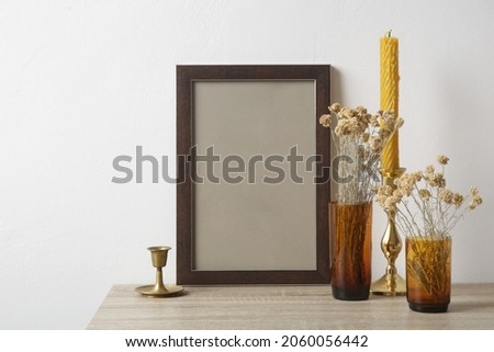 Wooden frame mockup on table with home interior decor elements. White wall background. Neutral color palette.