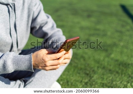 Cropped image of female hands with smartphone. She using a Fitness App on the Mobile Phone after workout.