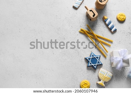 Tasty cookies for Hanukkah celebration with candles and dreidels on grey background