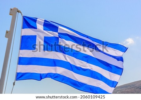 The Greek flag is waving on the mast of a ship
