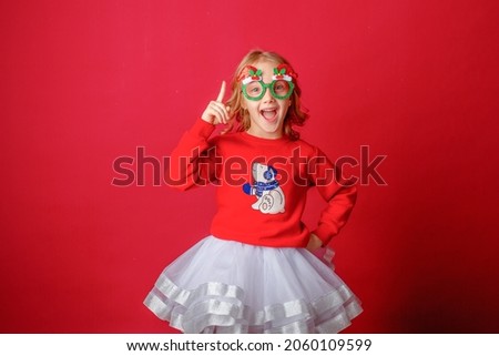 little girl on a red background in carnival christmas glasses 