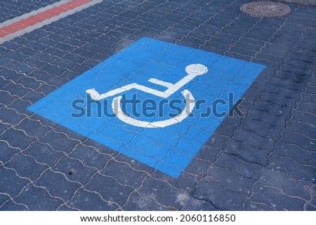 blue color disabled parking sign painting infographics in the parking lot on the asphalt in front of a supermarket in Budapest suburb, Hungary
