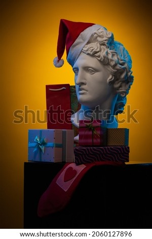 Design for postcards for Christmas and New Year. White plaster sculpture of a bust of Apollo wearing a red cap of Santa Claus