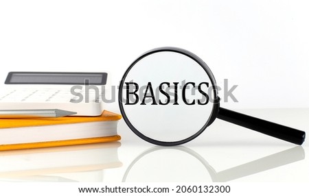 Magnifier with text BASICS with notebook, calculator on white background
