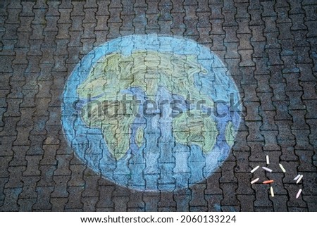 Earth globe painting with colorful chalks on ground. PHappy earth day concept. Creation of children for saving world, environment and ecology.