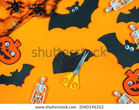 Getting ready for Halloween, carving bats. Background with bats, pumpkins and skeletons.