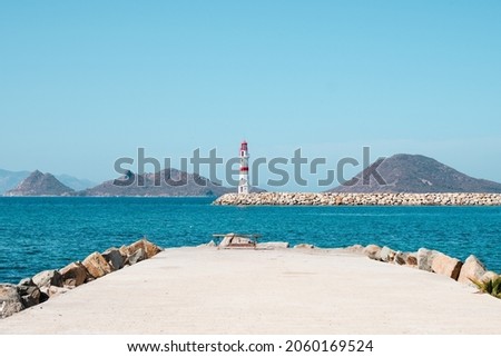 Lighthouse standing at the coast of Bodrum, Turkey. Red white lighthouse with islands on turquoise sea.