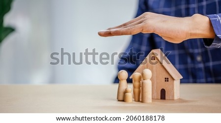 Insurance agent complete wooden model of the house with last piece with text insurance.Property (family house) insurance protection concept.