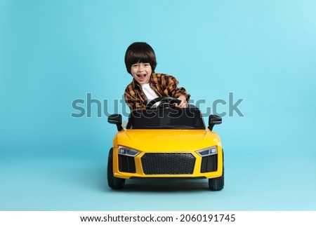 Little child driving yellow toy car on light blue background Royalty-Free Stock Photo #2060191745