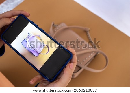 Young woman taking photo of bag with smartphone camera to sell on her website. Online product sales concept.