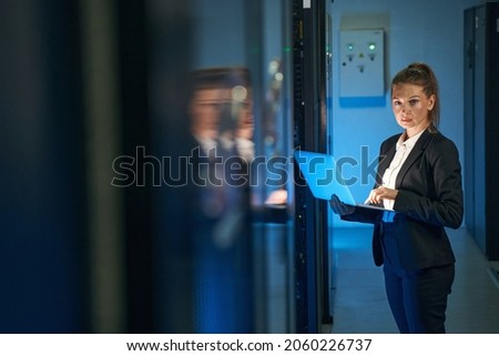 Female IT professional working in server room with laptop Royalty-Free Stock Photo #2060226737