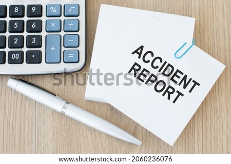 note paper with text Accident Report on the wooden table beside the calculator