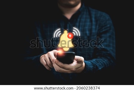 Businessman holding smartphone with virtual yellow bell ringing for application notification alert concept. Royalty-Free Stock Photo #2060238374