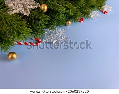 Christmas decorations, pine tree leaves, golden balls, snowflakes, red berries and golden berries on blue background
