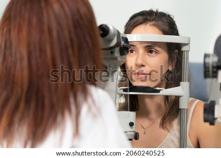 Optometrist woman examining the eyesight of another woman with a slit lamp Royalty-Free Stock Photo #2060240525