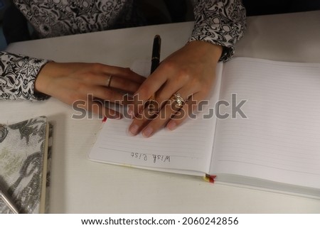 girl makes notes in a notebook. Goals, list of tasks, list of wishes. Hands with manicure, elegant pen, white shirt