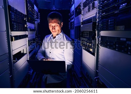 Data center IT worker staring at his notebook computer Royalty-Free Stock Photo #2060256611
